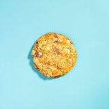 Bueno New York Cookie with chopped hazelnuts, white chocolate chips, and crispy feuilletine on a blue background.